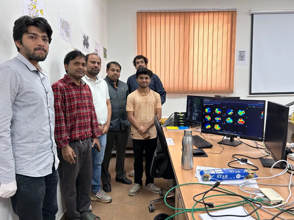 Group beside a laboratory measurement display